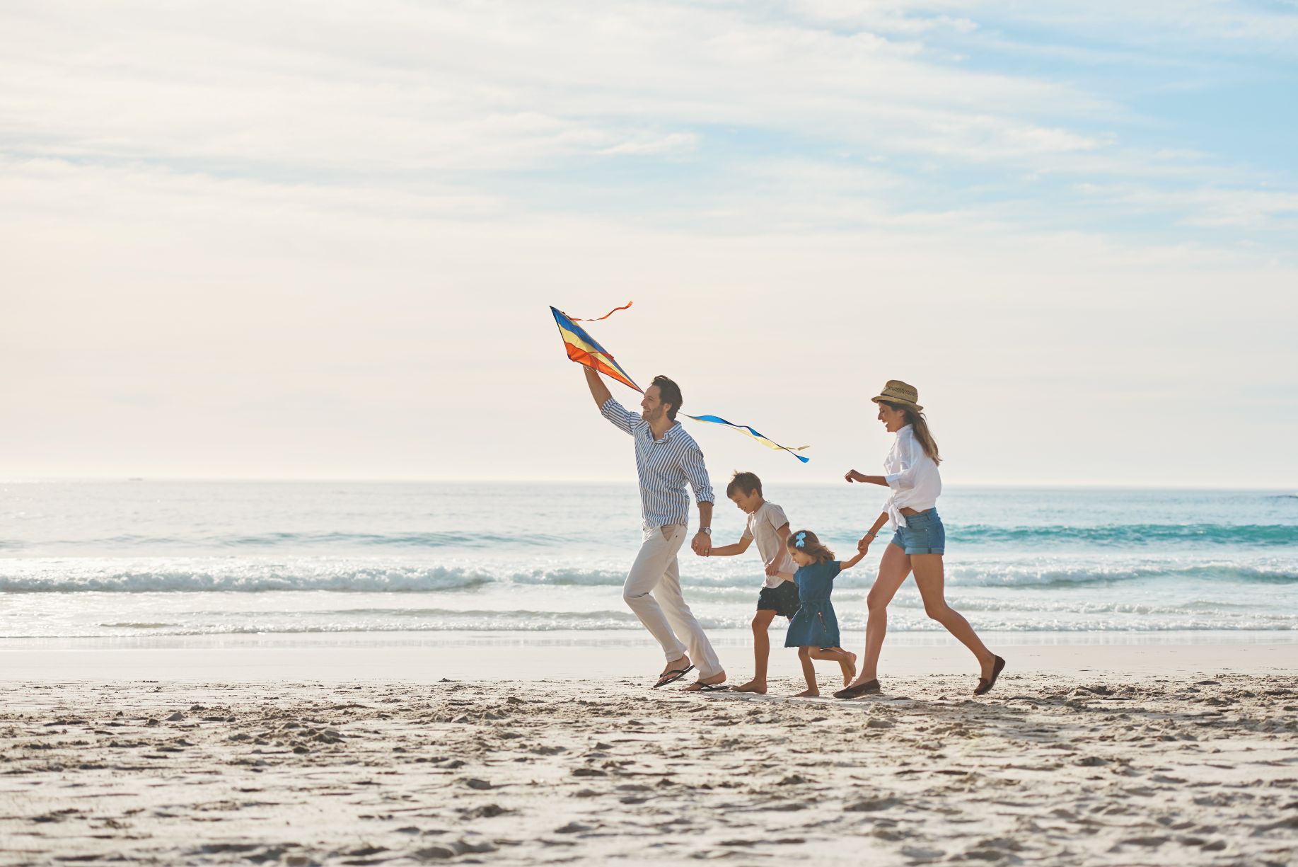 Family, holding hands and kite on beach
